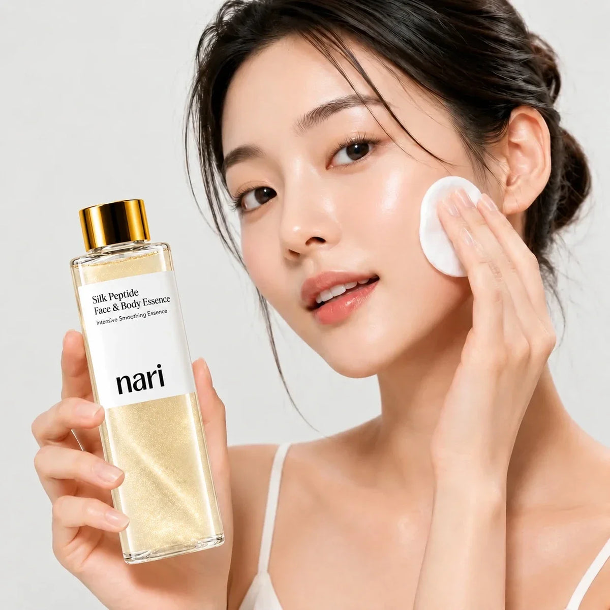 Woman applying nari Silk Peptide Face & Body Essence with a cotton pad